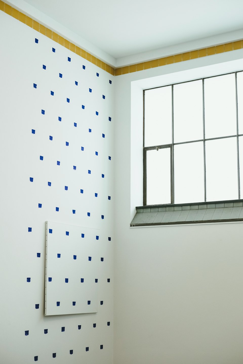 Minimalistische Zimmerecke mit blauen Mustern und großem Fenster.